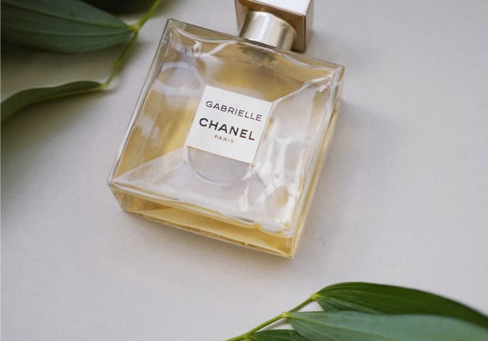 The Channel Gabrielle perfume positioned between green leaves